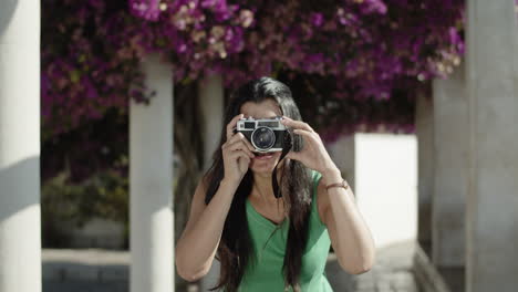 Front-view-of-young-Hispanic-woman-taking-photo-with-camera.